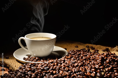 Coffee cup and coffee beans with smoke on burlap sack