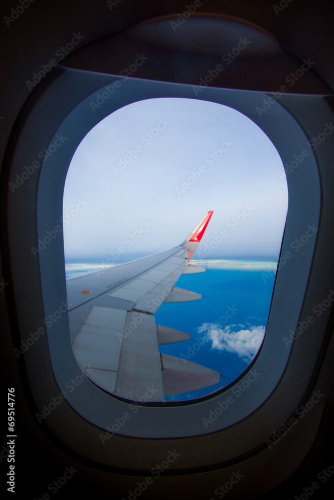 Wing of airplane flying above the clouds in the sky Wing of airplane flying above the clouds in the sky