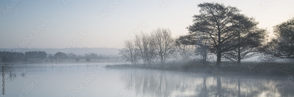 Panorama landscape of lake in mist with sun glow at sunrise Panorama landscape of lake in mist with sun glow at sunrise