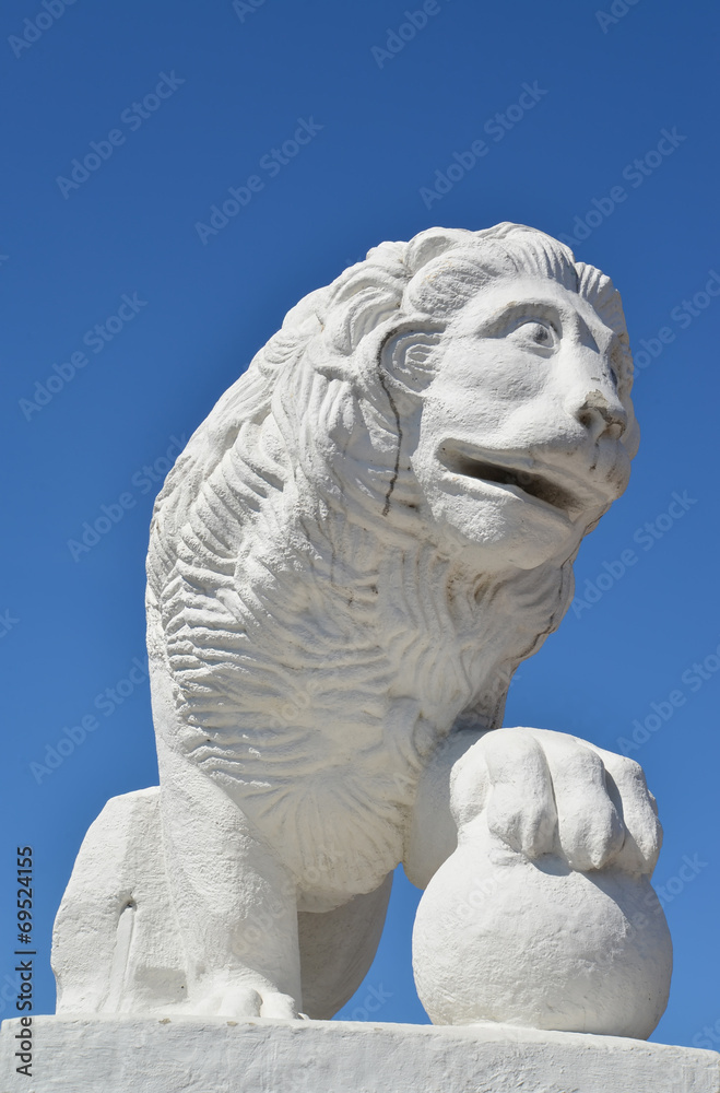 White stone lion with a sphere against the blue sky. St. Petersb
