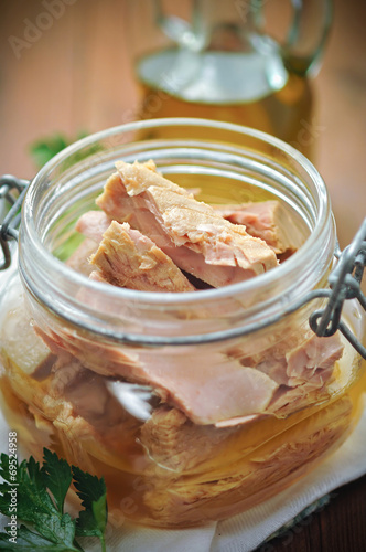 Tuna with parsley in a glass jar on wooden table
