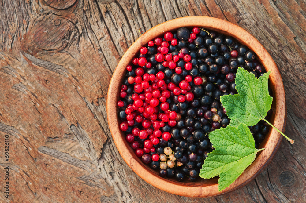 Bllack and red currant and green leaves in wooden bowl. Bllack and red currant and green leaves in wooden bowl.