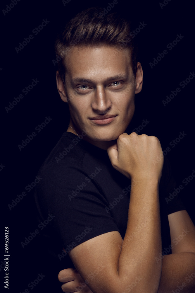 Cool young sexy man standing on dark background