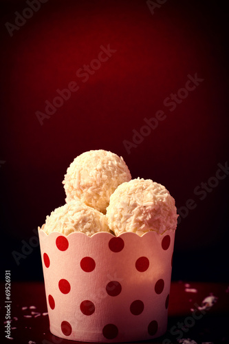 Coconut pralines in the cup on red background photo