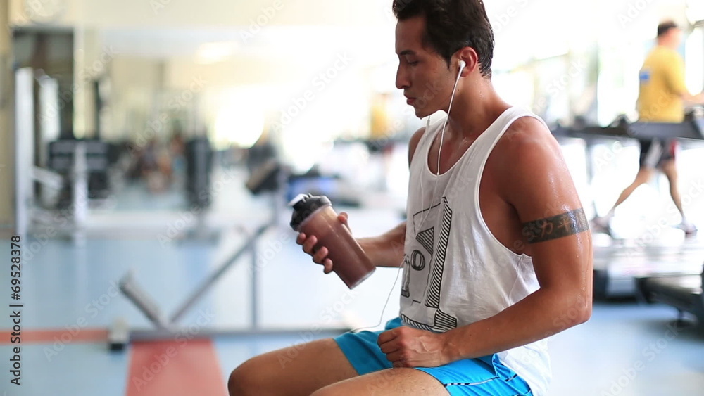 attractive young man drinking energy drink during a break at gym attractive young man drinking energy drink during a break at gym