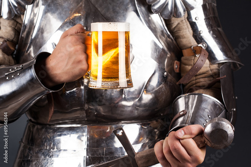 knight wearing armor and holding mug of beer and two-handed swor photo