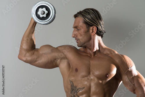 Mature Man Doing Exercise For Biceps On Grey Background © Jale Ibrak