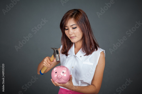 Beautiful Asian girl about to hit money box with hammer