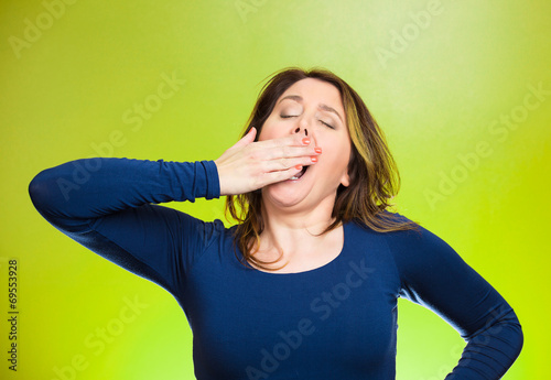 Sleep deprived young woman hand on mouth yawning