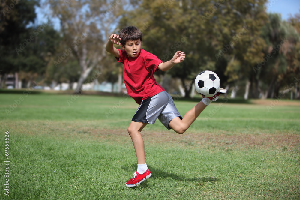 Boy in the park kickiing a soccer ball Boy in the park kickiing a soccer ball