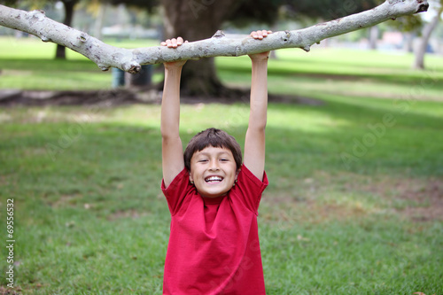 Boy in the park hanging from tree