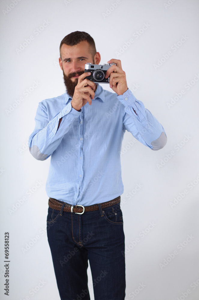Young beard man focusing at you with his camera while standing Young beard man focusing at you with his camera while standing