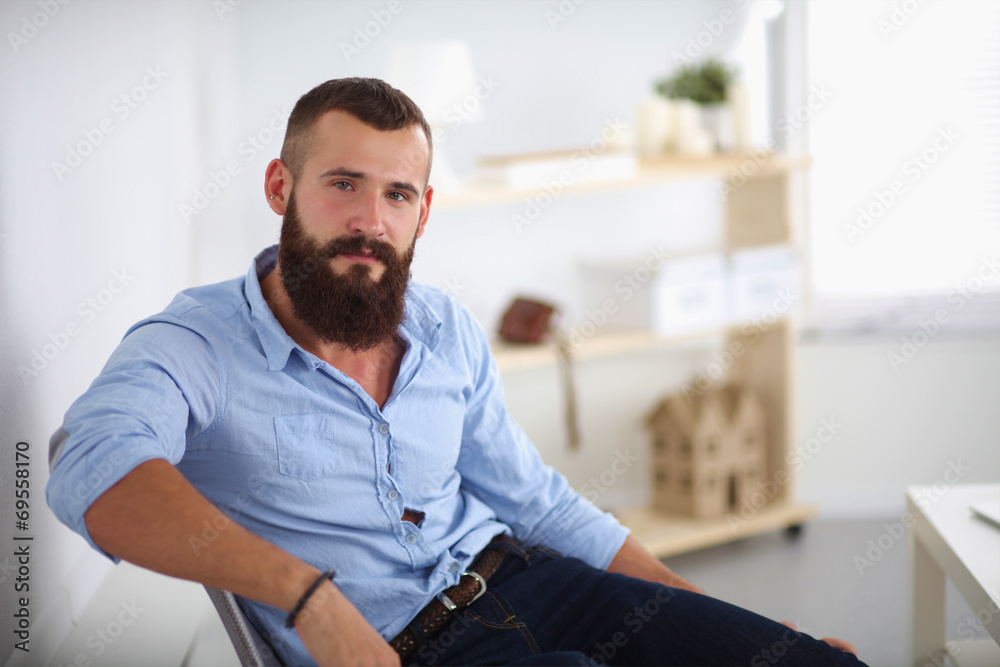 Fototapeta premium Young businessman sitting on chair in office