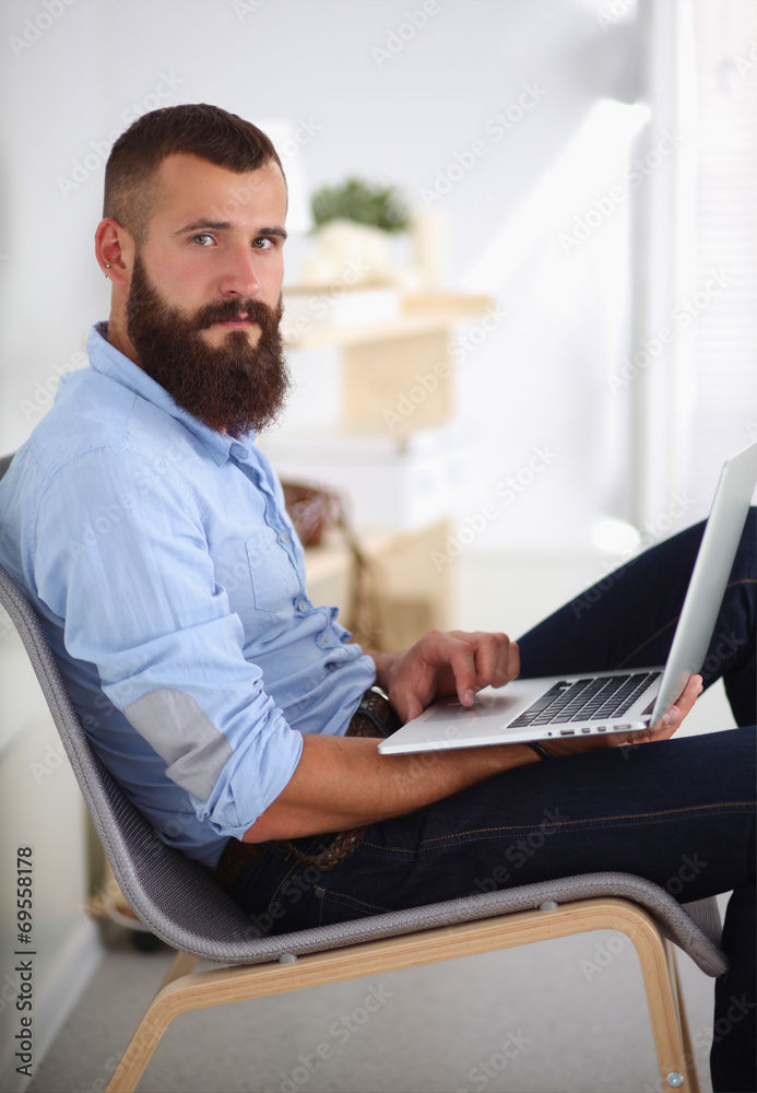 Handsome young man sitting and working on laptop computer. Handsome young man sitting and working on laptop computer.