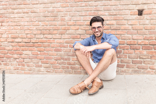 man sitting near brick wall and smiles