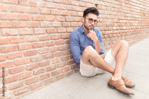 man looking pensive while sitting on the sidewalk