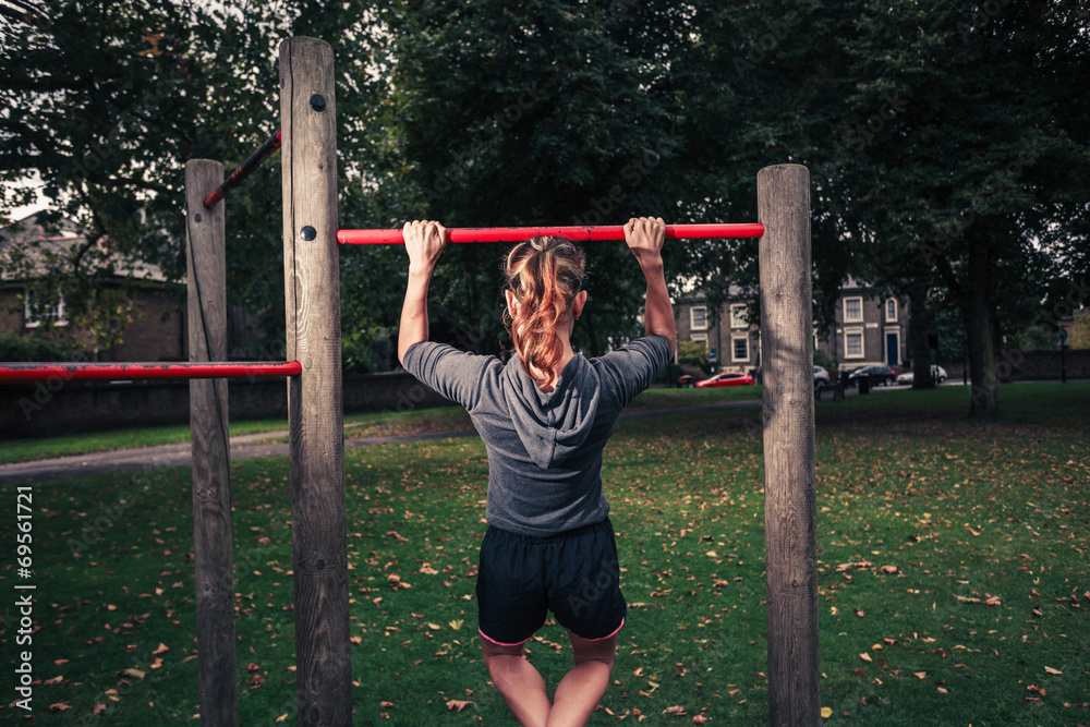 Young woman doing pullups in the park