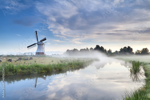 windmill and river in foggy morning