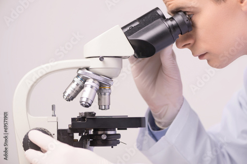 male scientist working in ab with microscope.