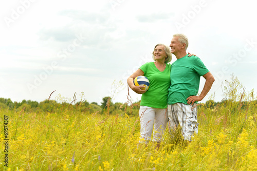 Senior couple in summer field with ball
