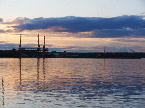 an industrial city on the shore of lake at sunset © enskanto