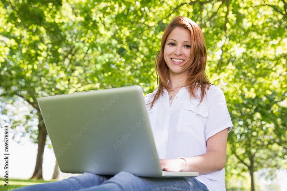 Pretty redhead using her laptop in the park Pretty redhead using her laptop in the park