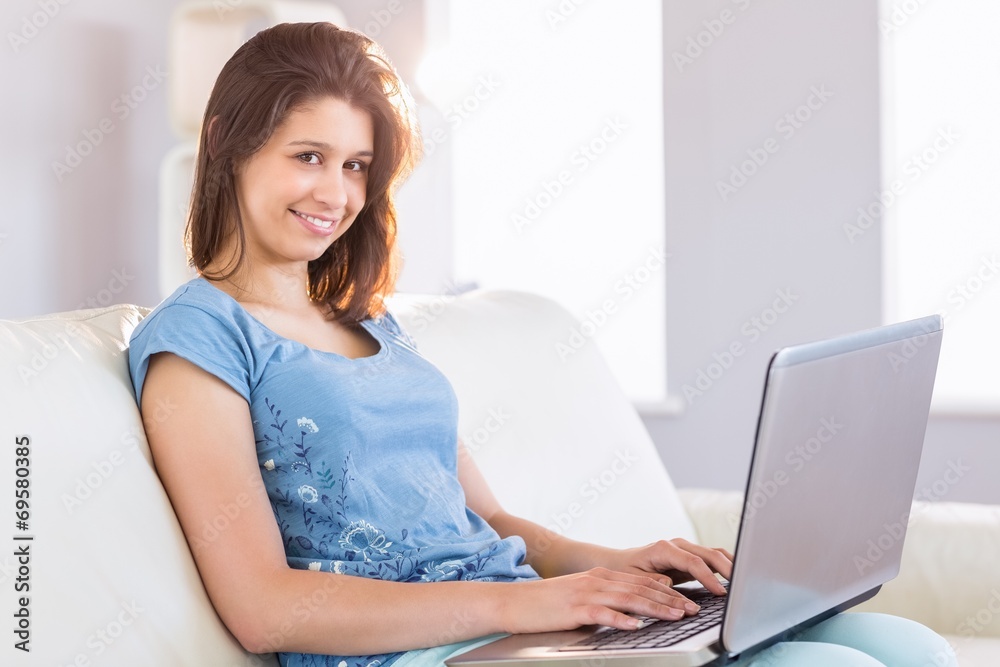 Pretty brunette relaxing on the couch using laptop Pretty brunette relaxing on the couch using laptop