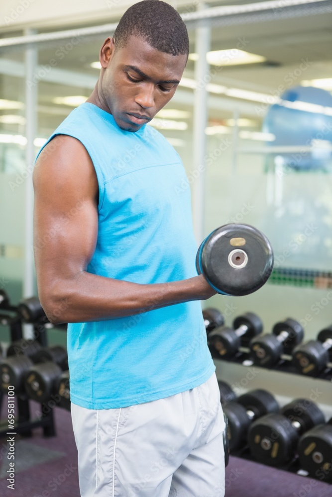 Young man exercising with dumbbell in gym Young man exercising with dumbbell in gym