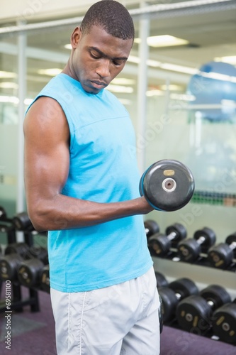 Young man exercising with dumbbell in gym