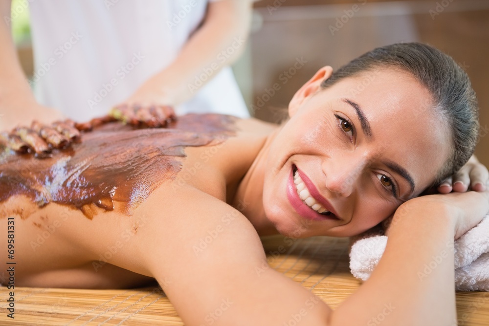 Obraz premium Attractive woman receiving chocolate back mask at spa center