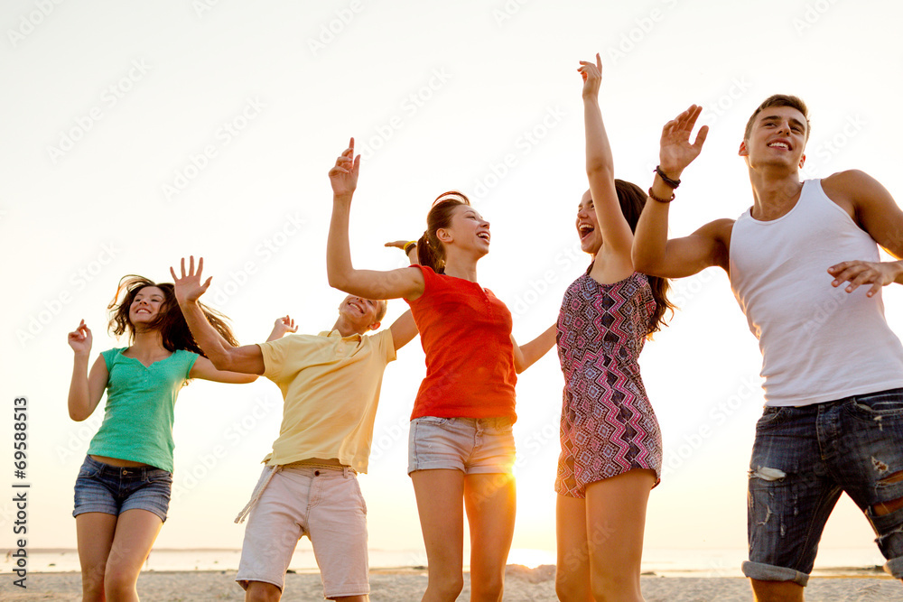Obraz premium smiling friends dancing on summer beach