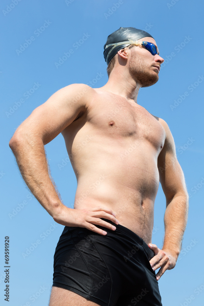 Swimmer with swimming goggles posing with blue sky