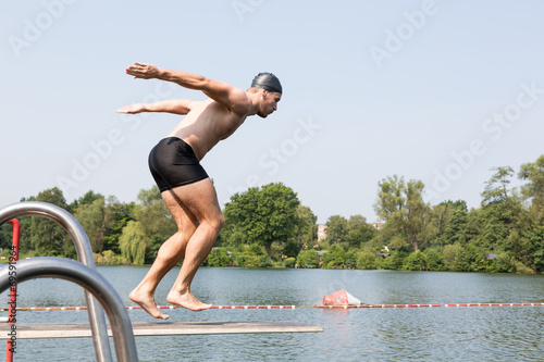 Man jumping off diving board at swimming pool
