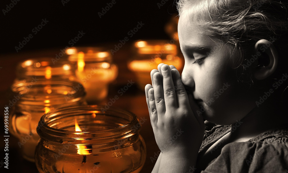 Praying child with candles on background.
