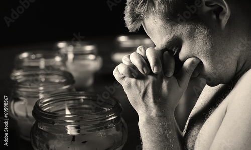 Praying man with candles on background.