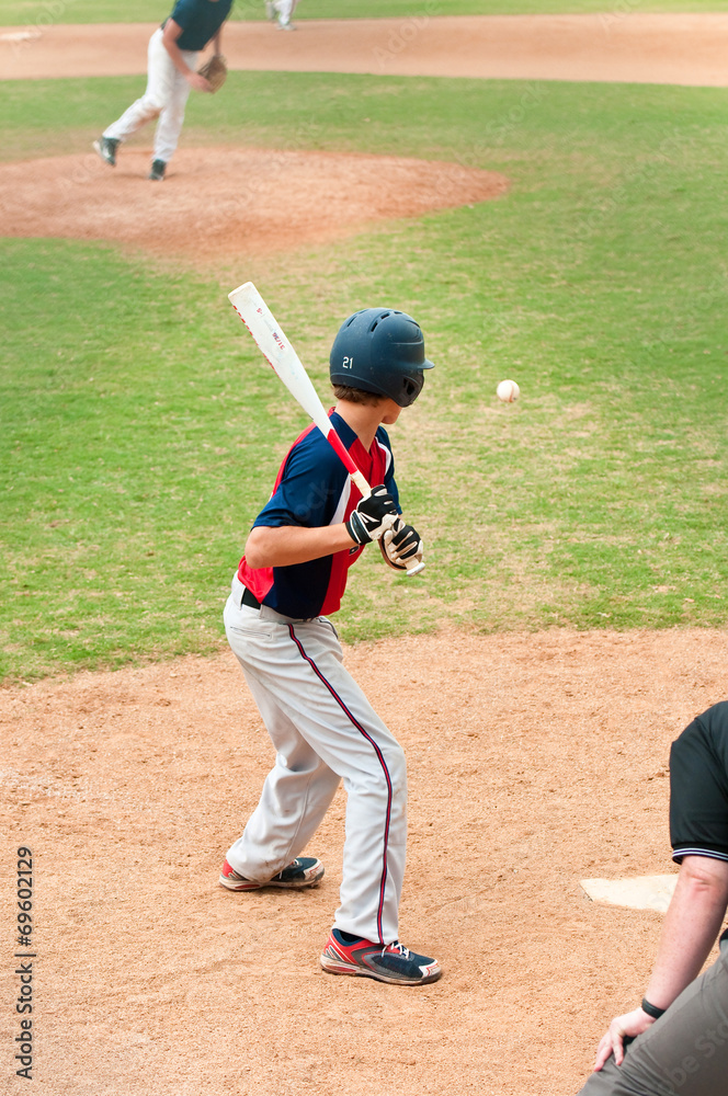 Teen player watching baseball at bat