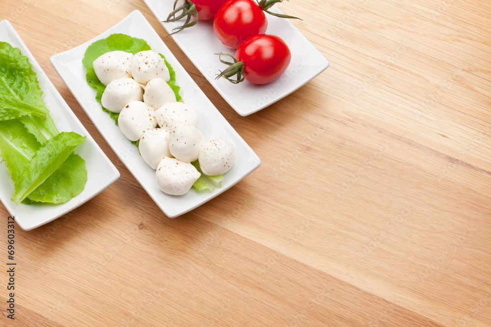 Tomatoes, mozzarella and green salad leaves Tomatoes, mozzarella and green salad leaves