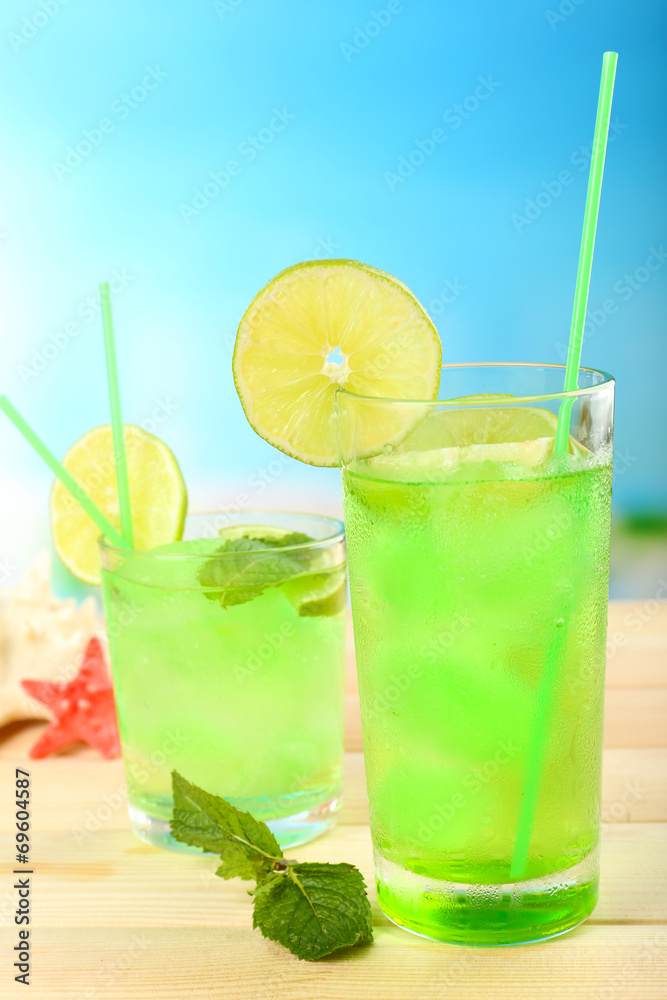 Refreshing cocktail on wooden table on blue background Refreshing cocktail on wooden table on blue background