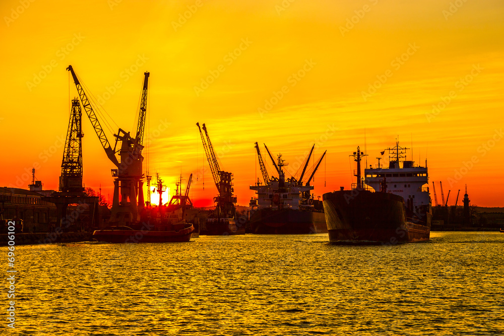 Fototapeta premium Silhouette of sea port cranes over sunset