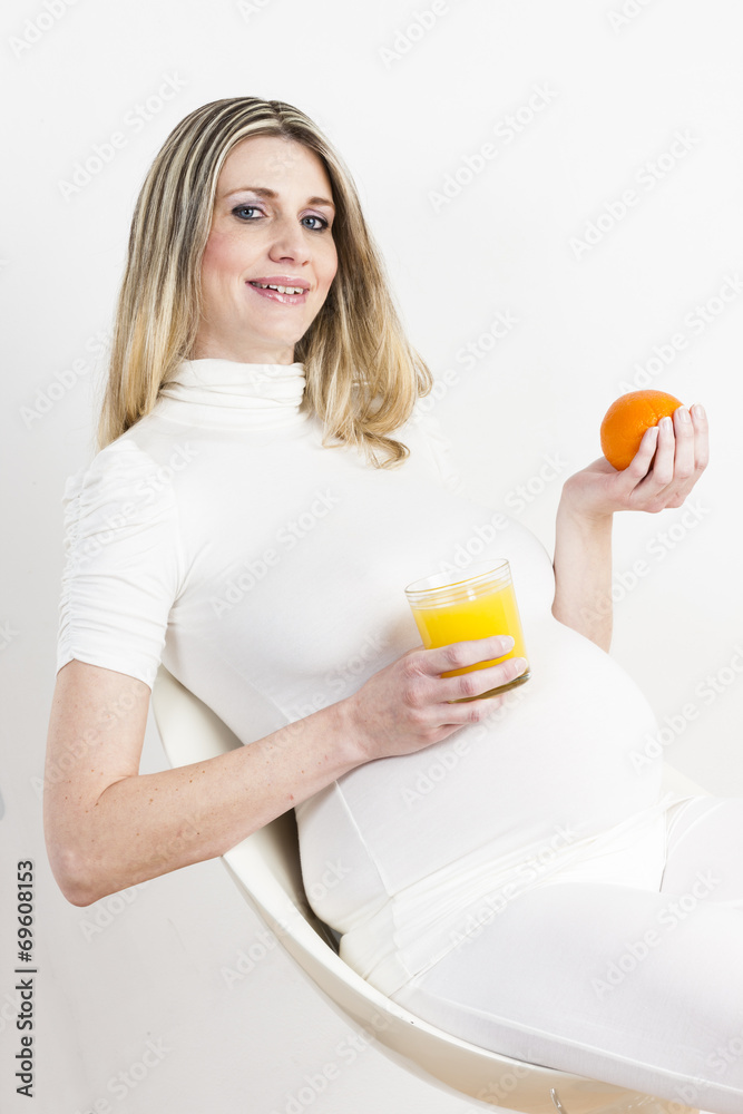 portrait of pregnant woman with a glass of orange juice and an o