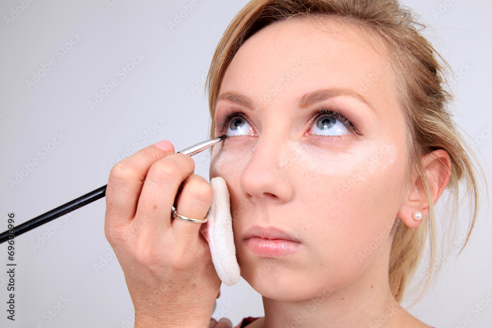 Fototapeta premium Makeup artist applying makeup to model