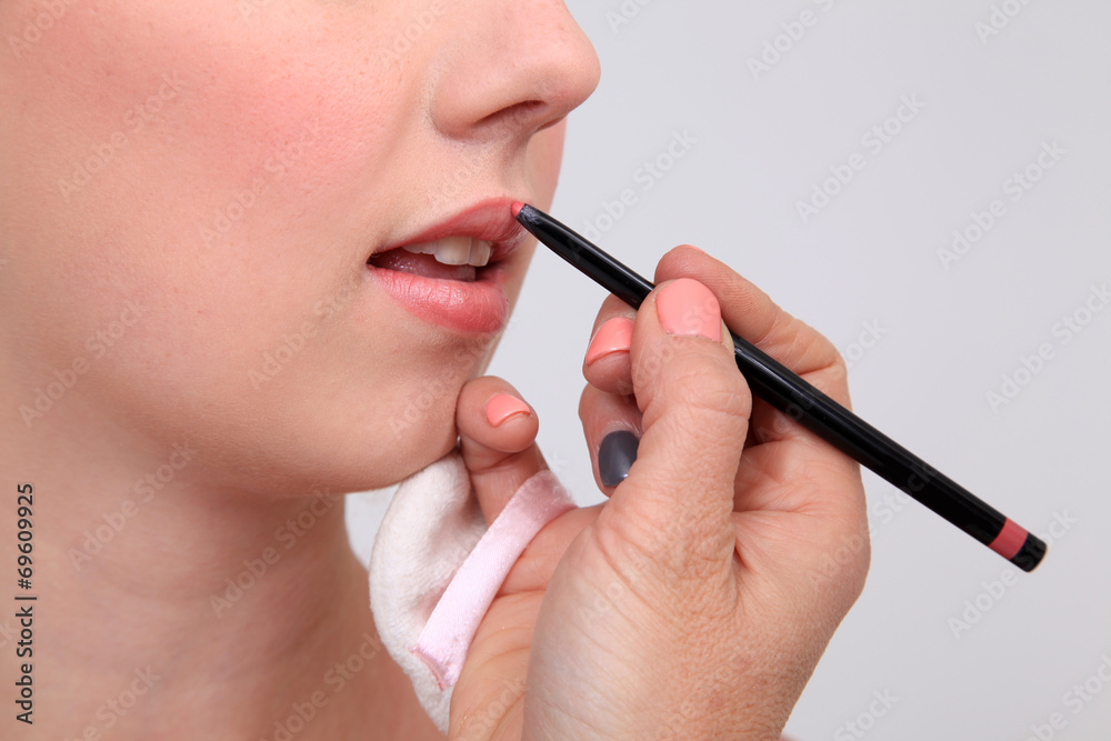 Makeup artist applying lipstick to model