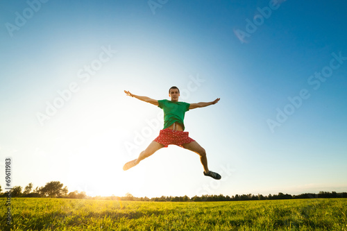 Young man jumping on meadow with dandelions © fotomaximum