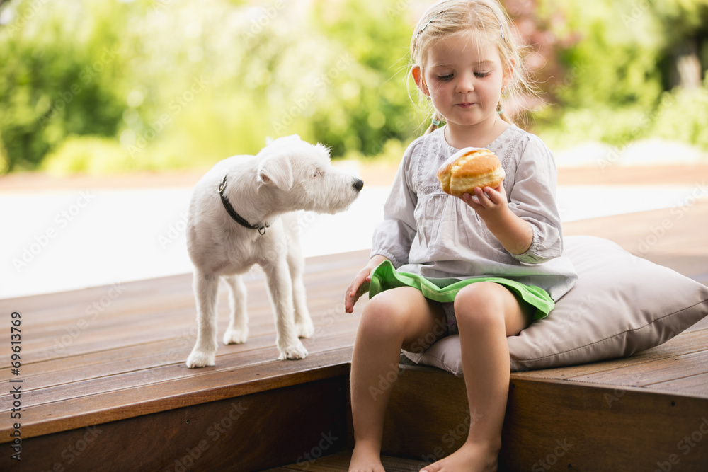 Mädchen sitzt draußen auf Holztreppe mit Hund