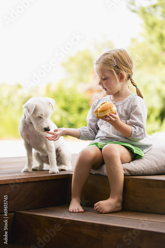 Mädchen sitzt draußen auf Holztreppe mit Hund