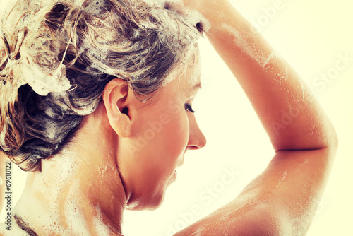 Beautiful woman taking a shower and shampooing her hair.
