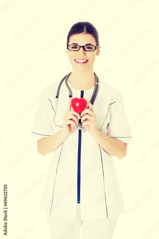 Beautiful young female doctor holding a heart.