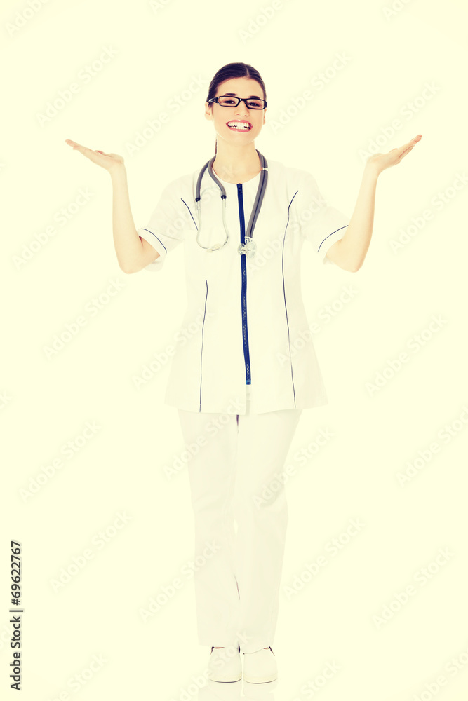 Young beautiful female doctor showing on copy space. Young beautiful female doctor showing on copy space.