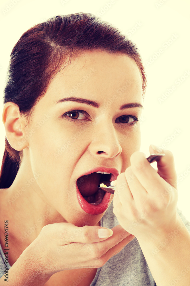 Young casual woman eating pills on a spoon. Young casual woman eating pills on a spoon.