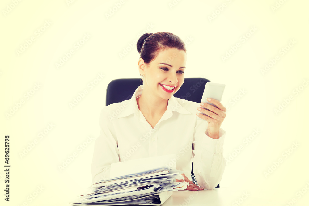 Beautiful business woman sitting by a desk with stack of papers. Beautiful business woman sitting by a desk with stack of papers.